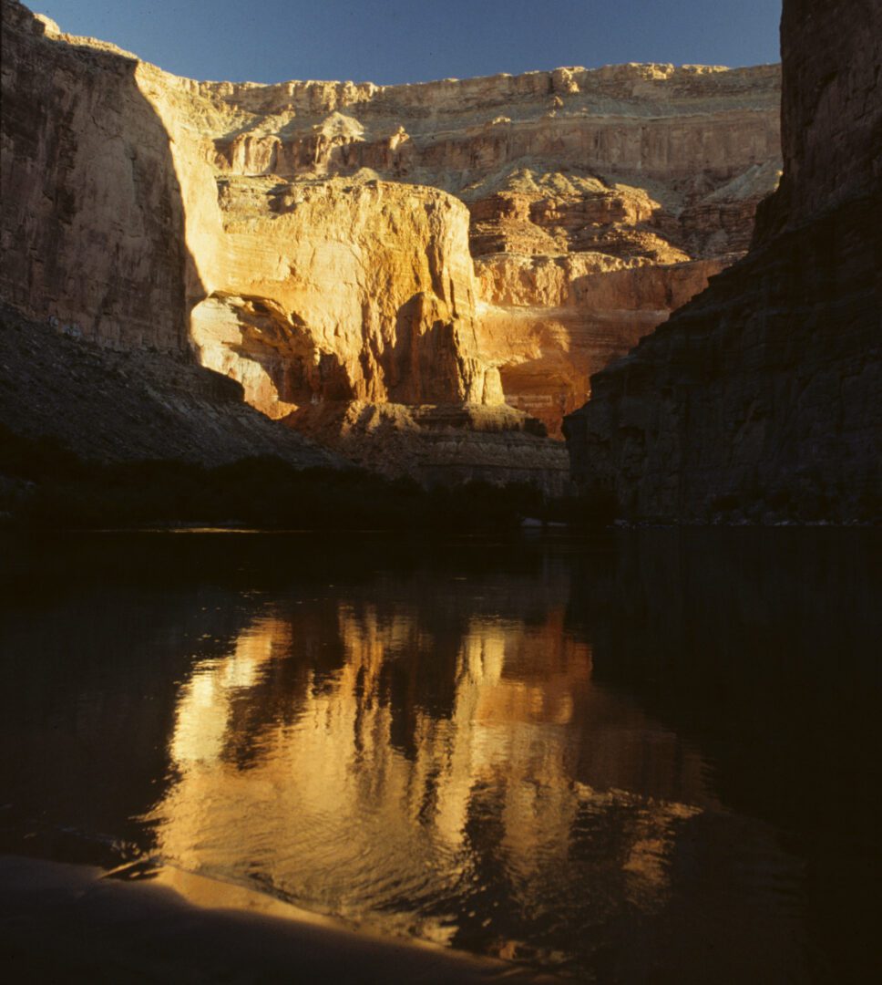 A river with water flowing through it and rocks in the background.