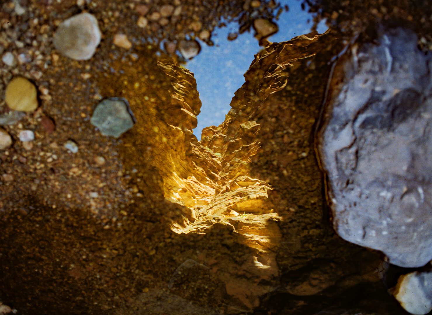 A puddle of water reflecting the sky and rocks.