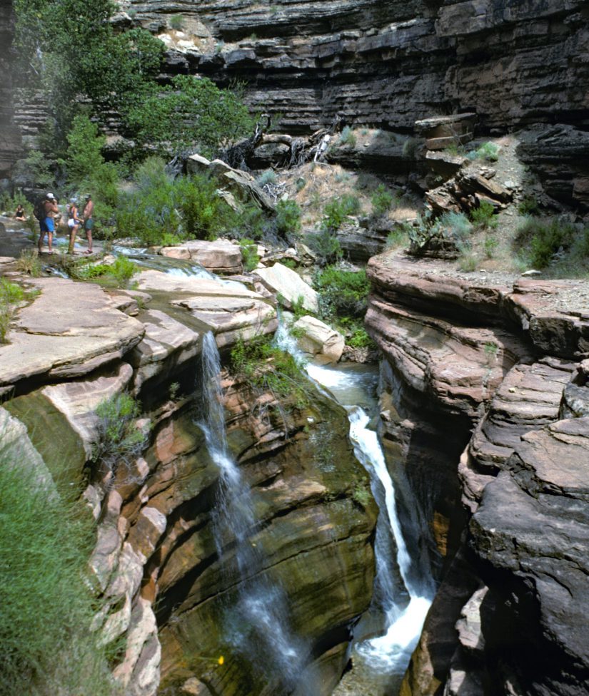 A waterfall is shown in the middle of a canyon.