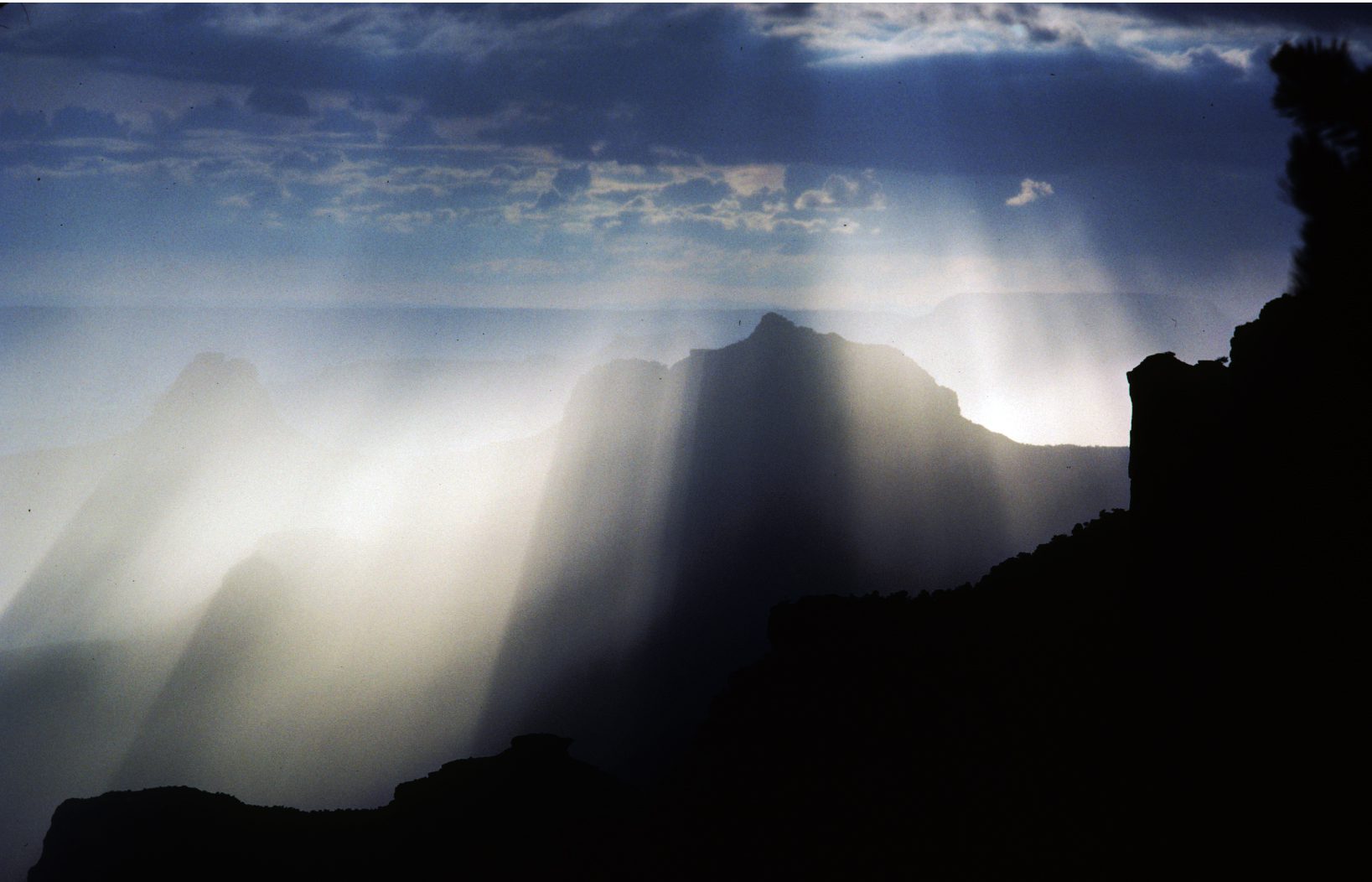 A mountain with sun rays coming through the clouds.