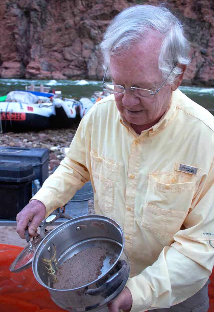 A man in yellow shirt holding a pan.